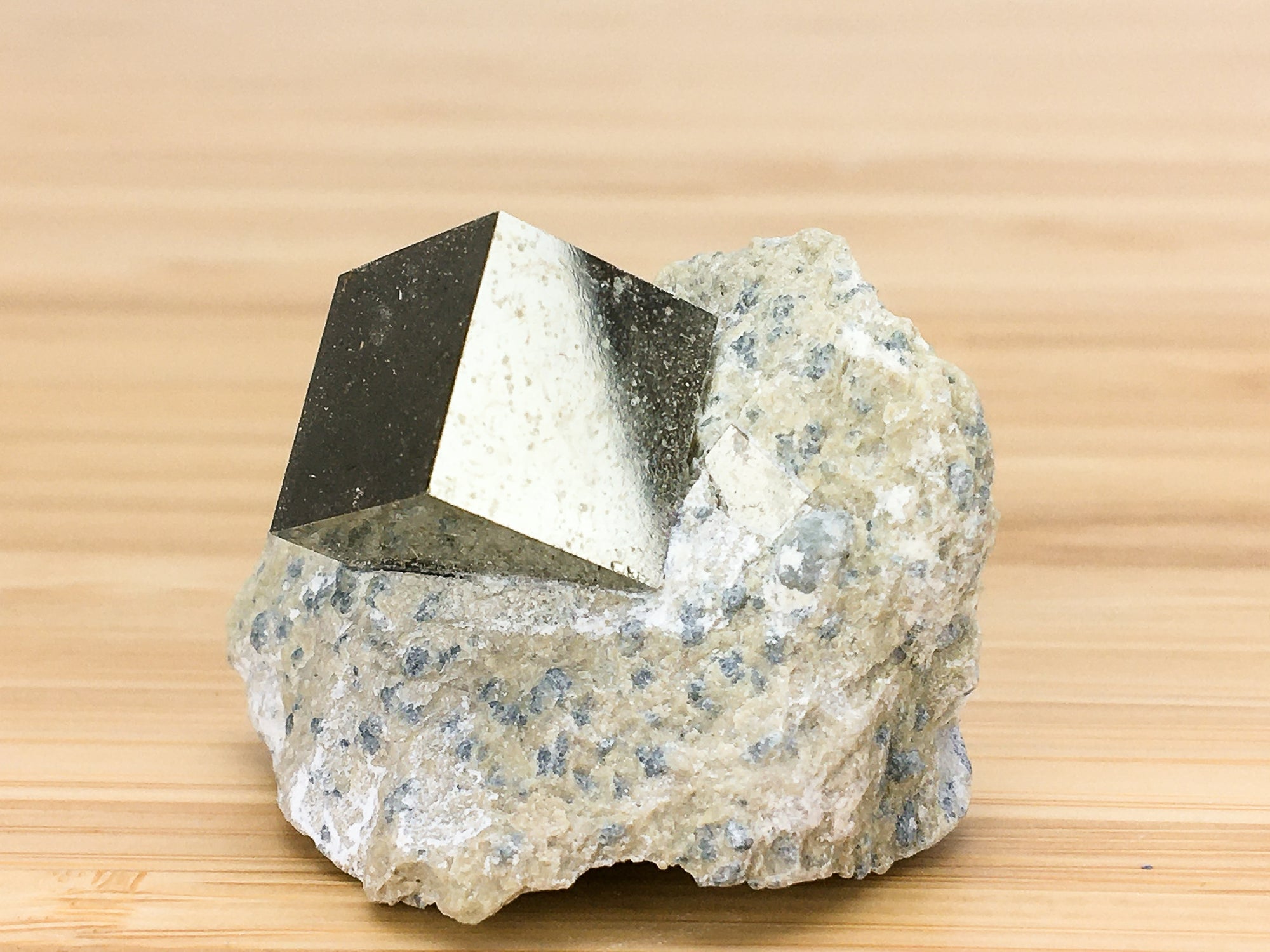 Naturally occurring cubic crystal of iron pyrite in marl matrix