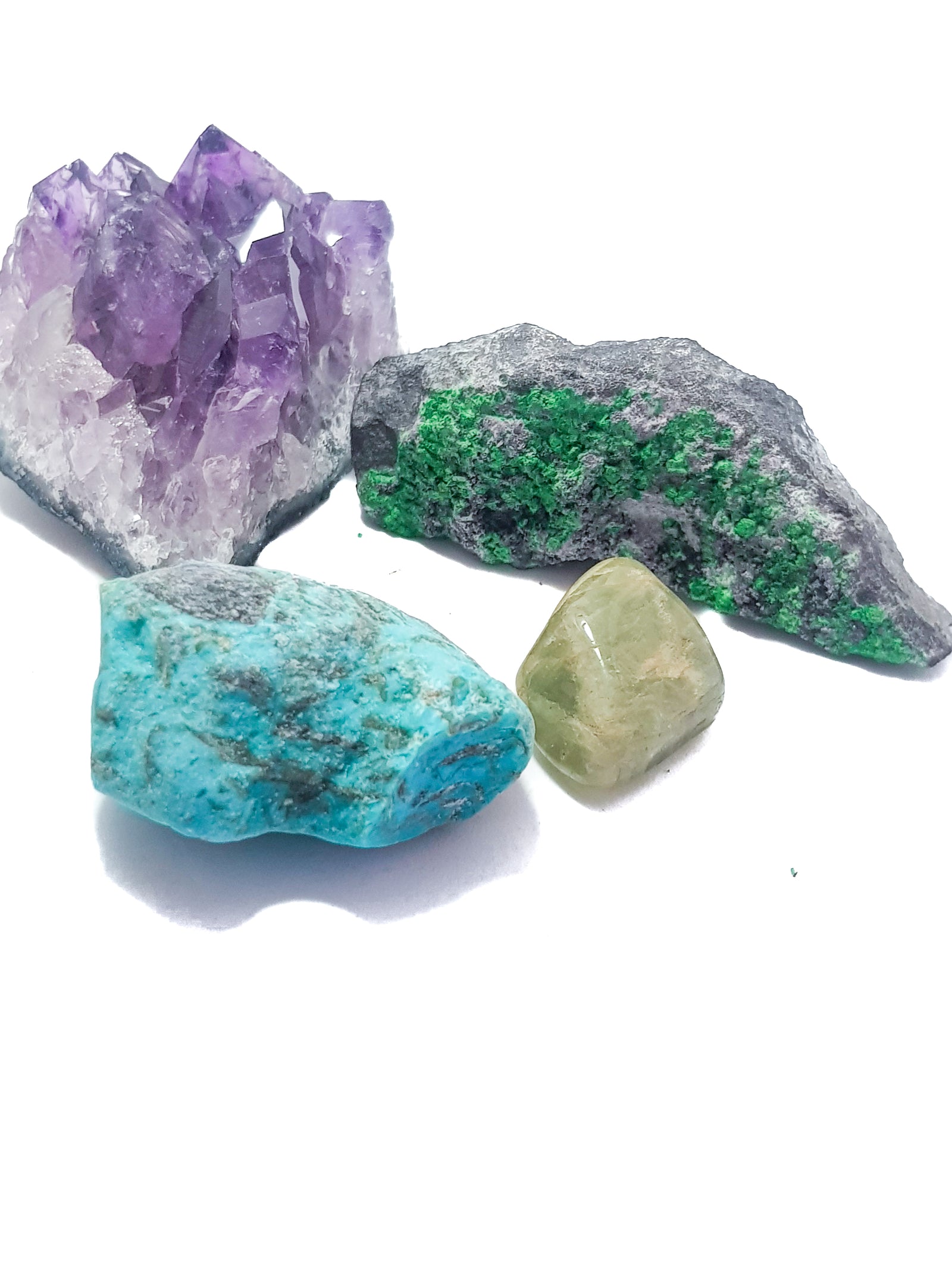 A photograph of four traditional birthstone. top left hand corner -- druzy amethyst; bottom left hand sample -- raw turquoise; top right hand corner -- uvarovite garnet on matrix; bottom right hand corner -- tumbled aquamarine