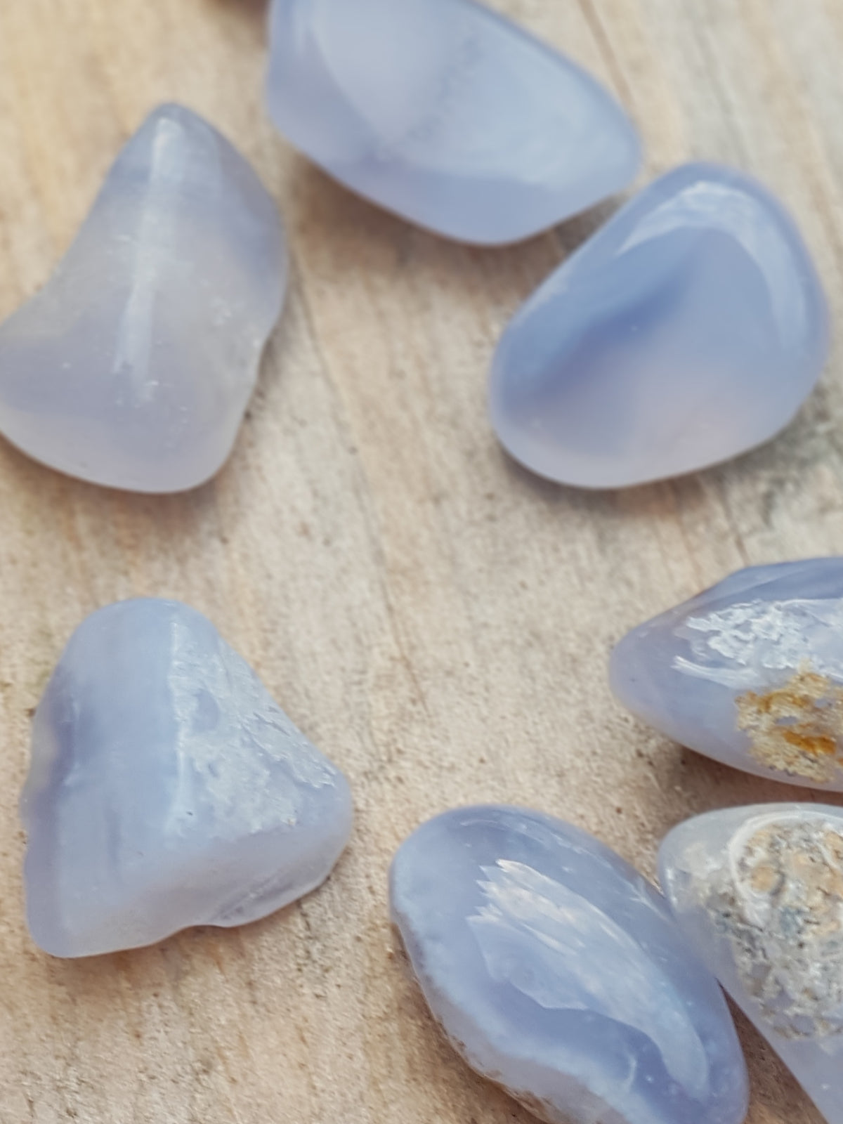 Seven small polished pieces of blue chalcedony. They are translucent. They are blue with some colour banding 