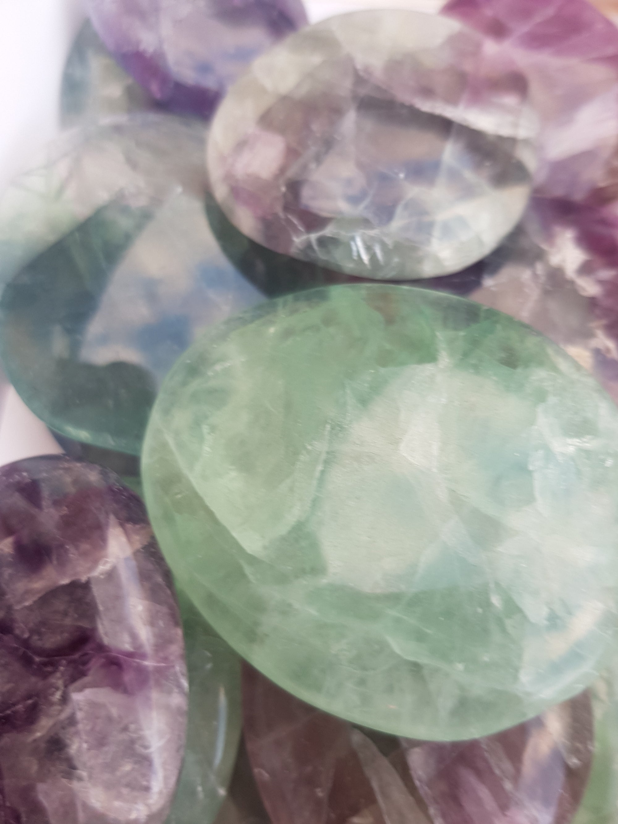 Rainbow fluorite palmstones. translucent flat and smooth. colour varies from green to purple in a single piece