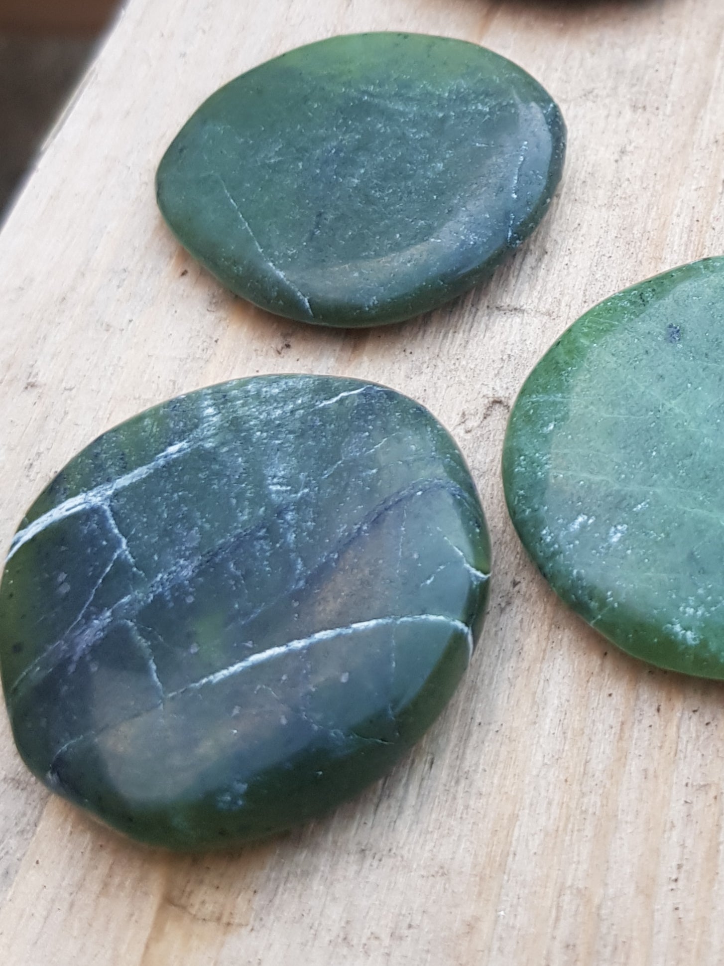 nephrite jade palmstone. dark green with some white lineations.