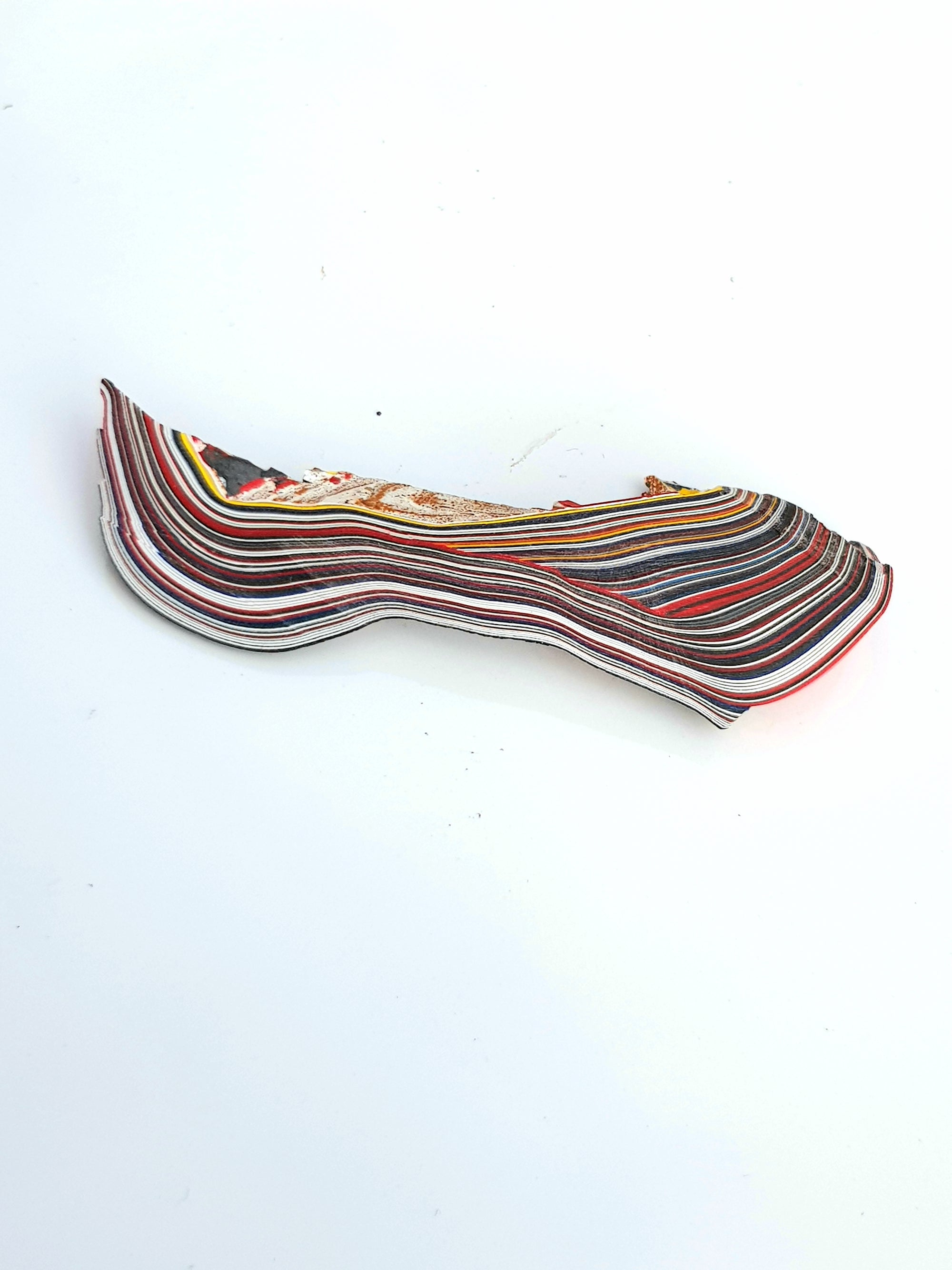 a sample of Fordite. It has red, blue and white layers, there is also a roughened centre - The Science of Magic 