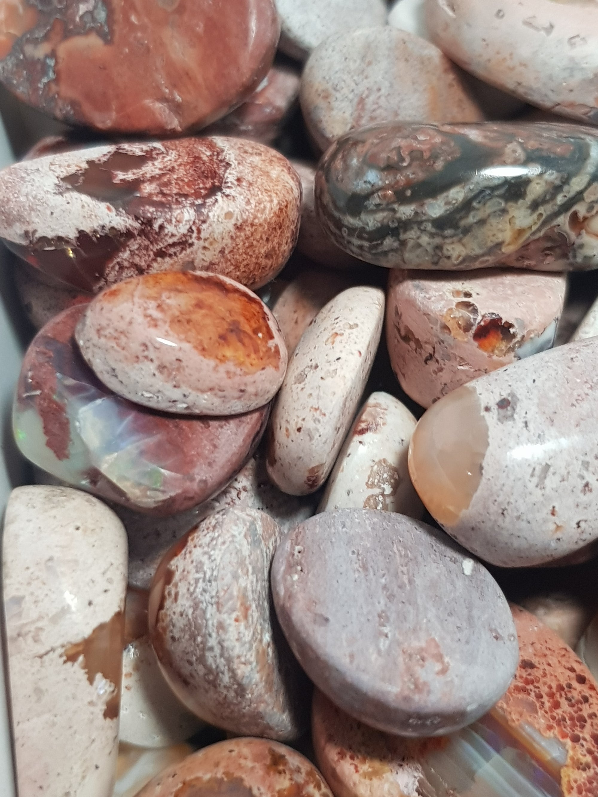 box of mexican fire opals in rhyolite. The opals are mostly red, but there are some blue pieces