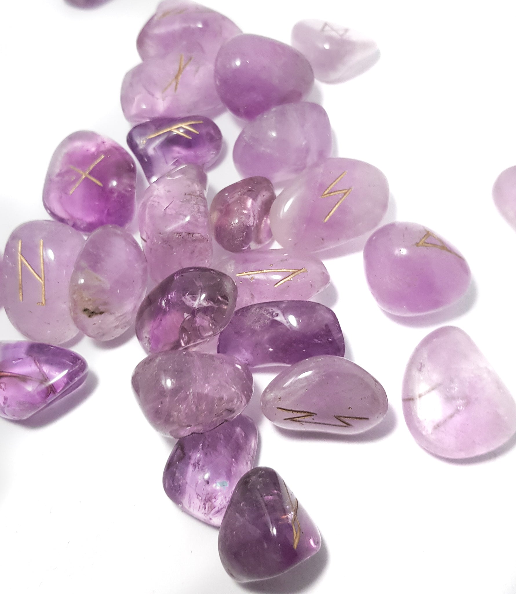 scattered set of amethyst rune stones. The pieces are purple the runic inscriptions are gold. -- science of magic