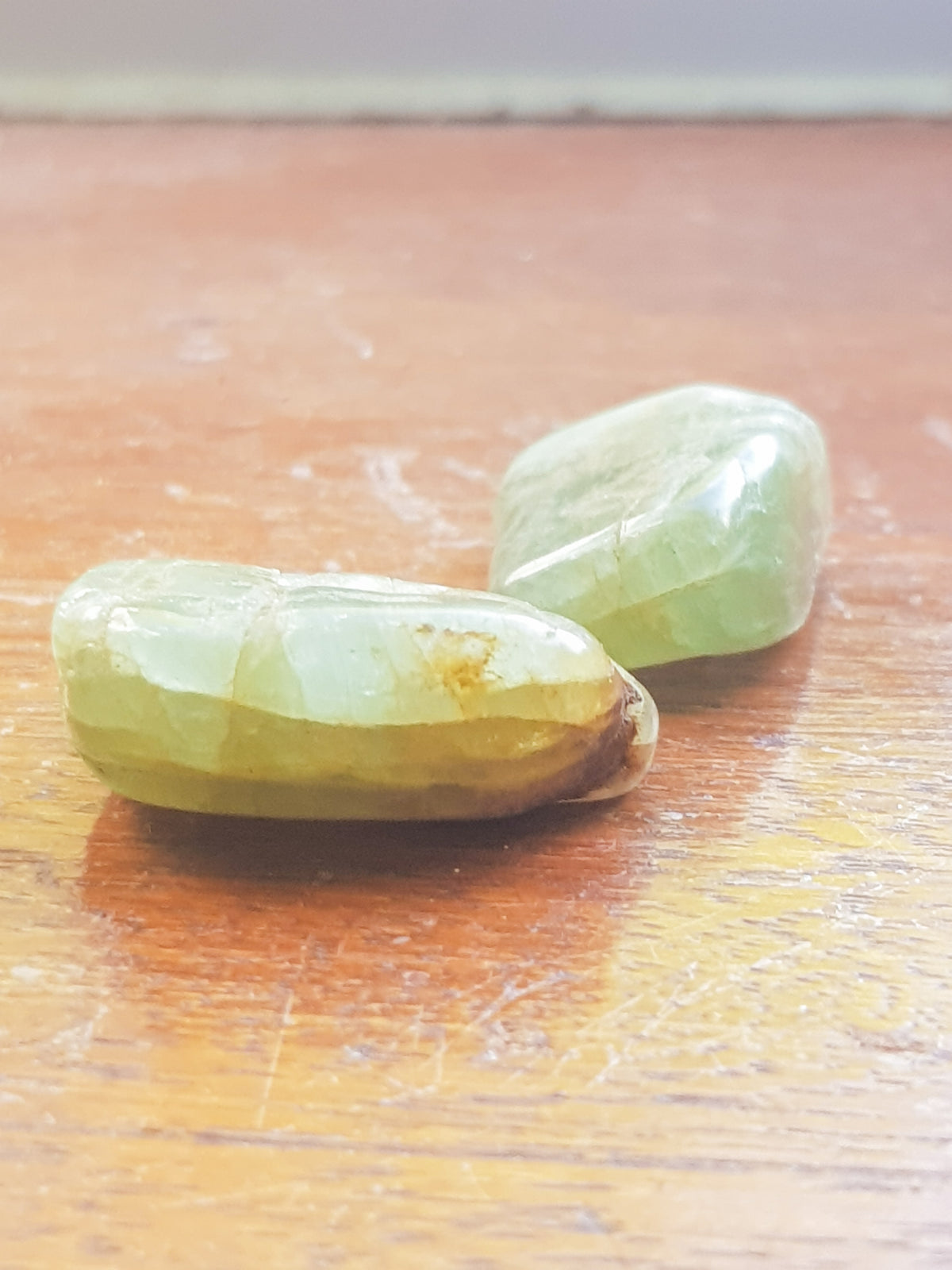 two green aquamarine tumblestones or a dark wood grained surface