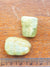 two green aquamarine tumblestones. They are placed against a ruler for scale. They are about 2.5cm long.