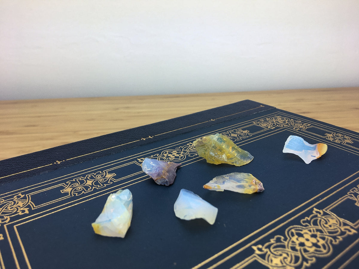 blue opalescent chips of raw Ethiopian fire opal on a black leatherbound book. 