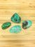 four pieces of apples green chrysoprase on a light wood grained surface