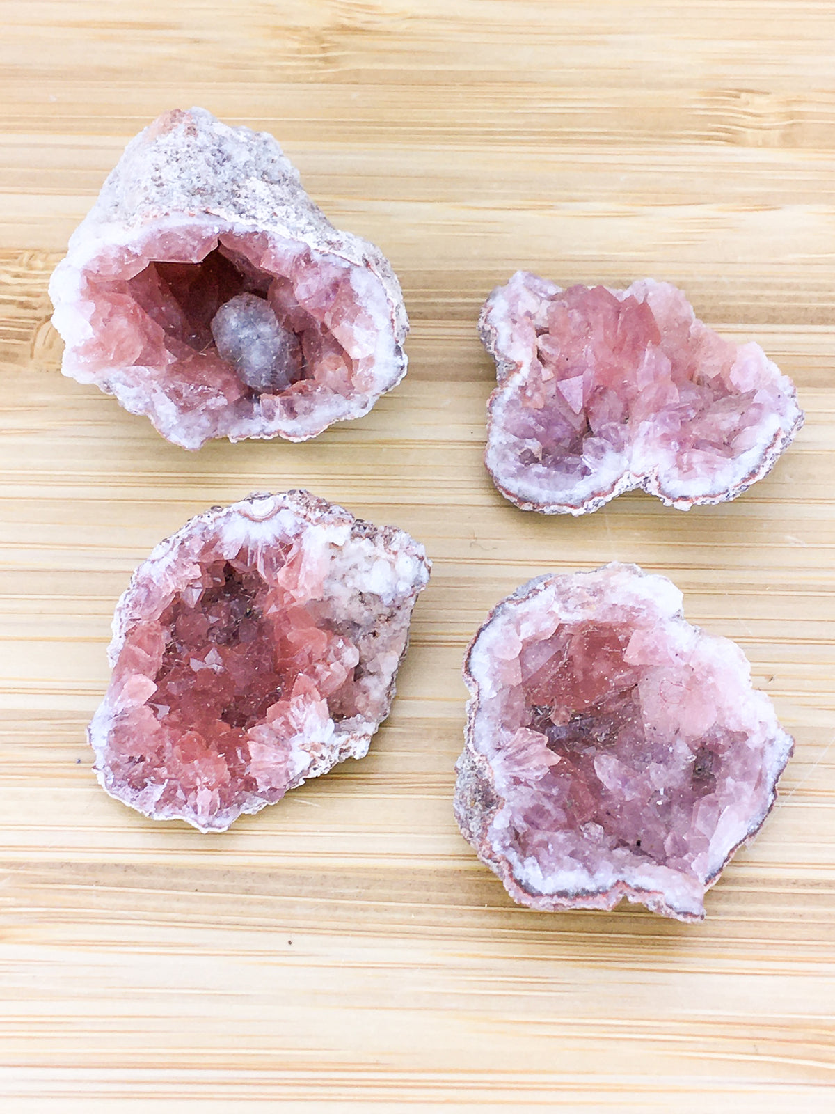 four geodes filled with pink amethyst crystals