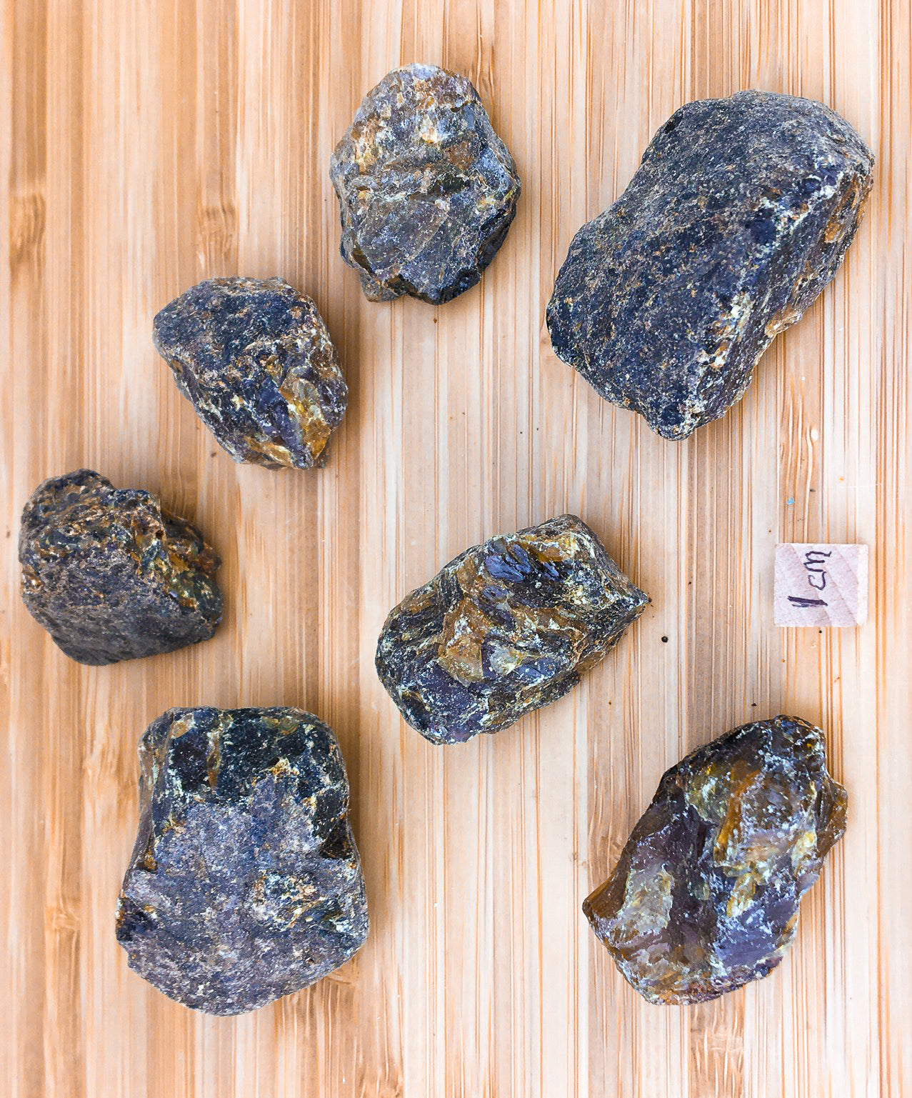 seven samples of raw amber from Sumatra. the samples appear dark, but have golden highlights