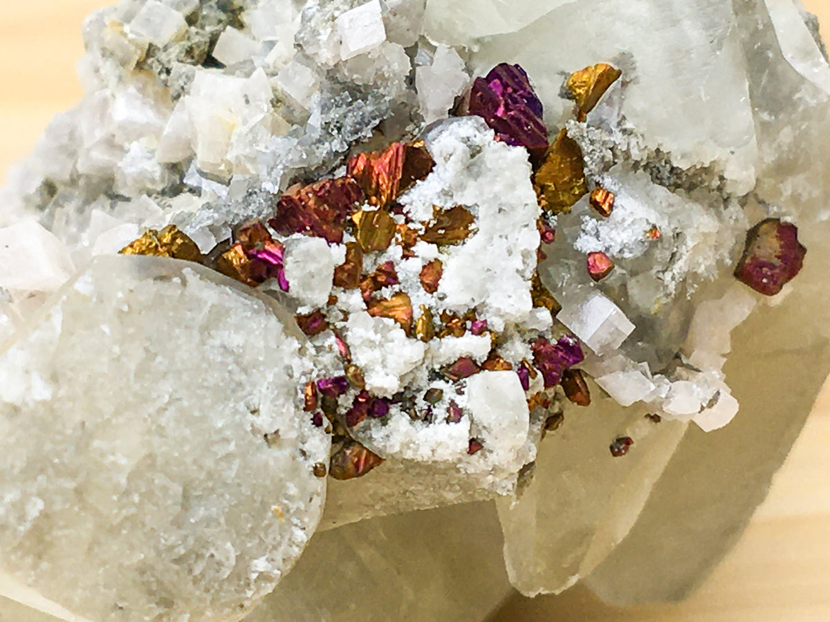 a close up of oxidised purple and orange chalcopyrite crystals which are growing on calcite