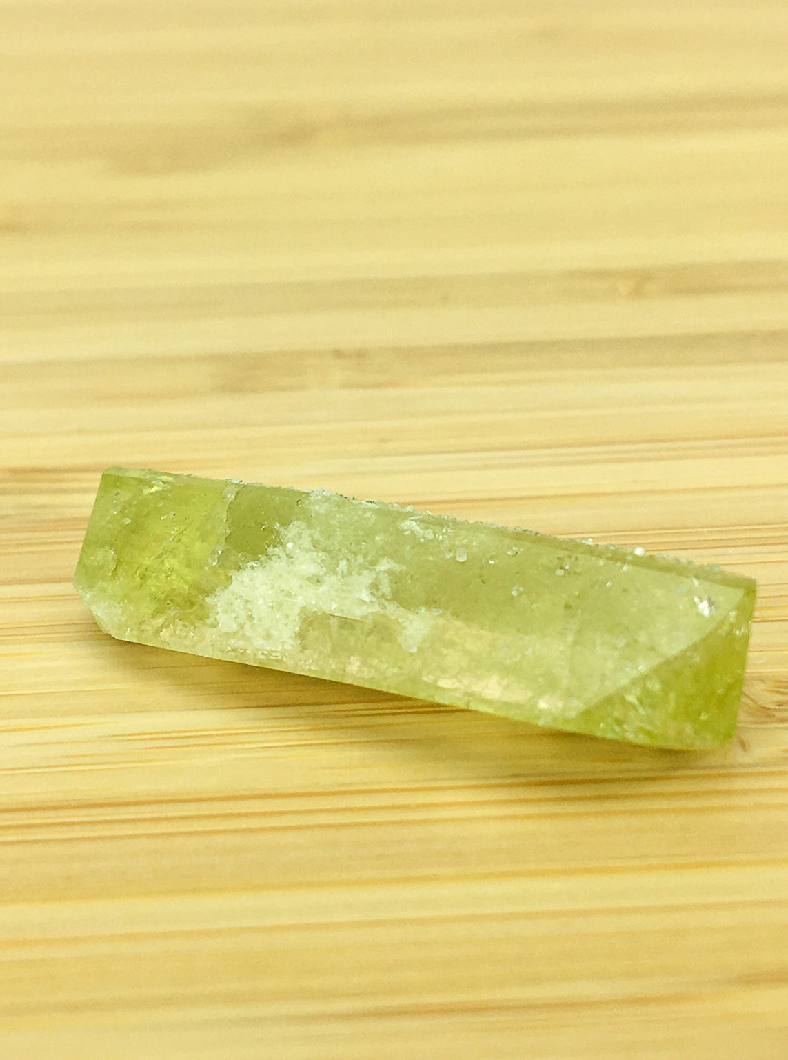 prismatic brazilianite crystal on a good grain surface. The crystal is prismatic and well formed. It is  green. It is gemmy.