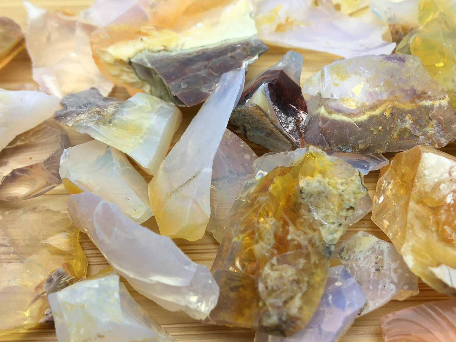 A close up of chips of Ethiopian fire opal. They vary in colour from blue to gold and are opalescent.