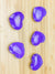 Five purple howlite hearts on a light wood grained surface
