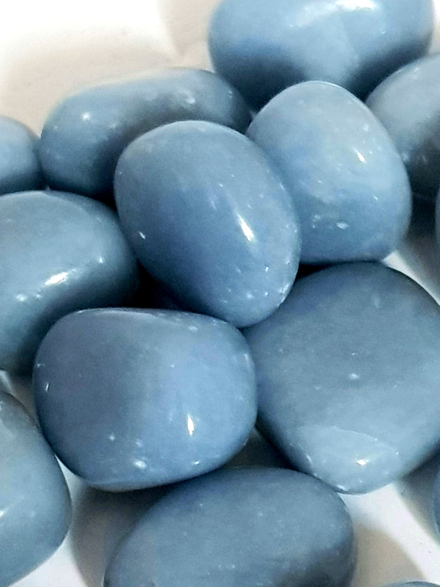 close up of anhydrite tumblestones. They are blue grey and have a slightly greasy texture.