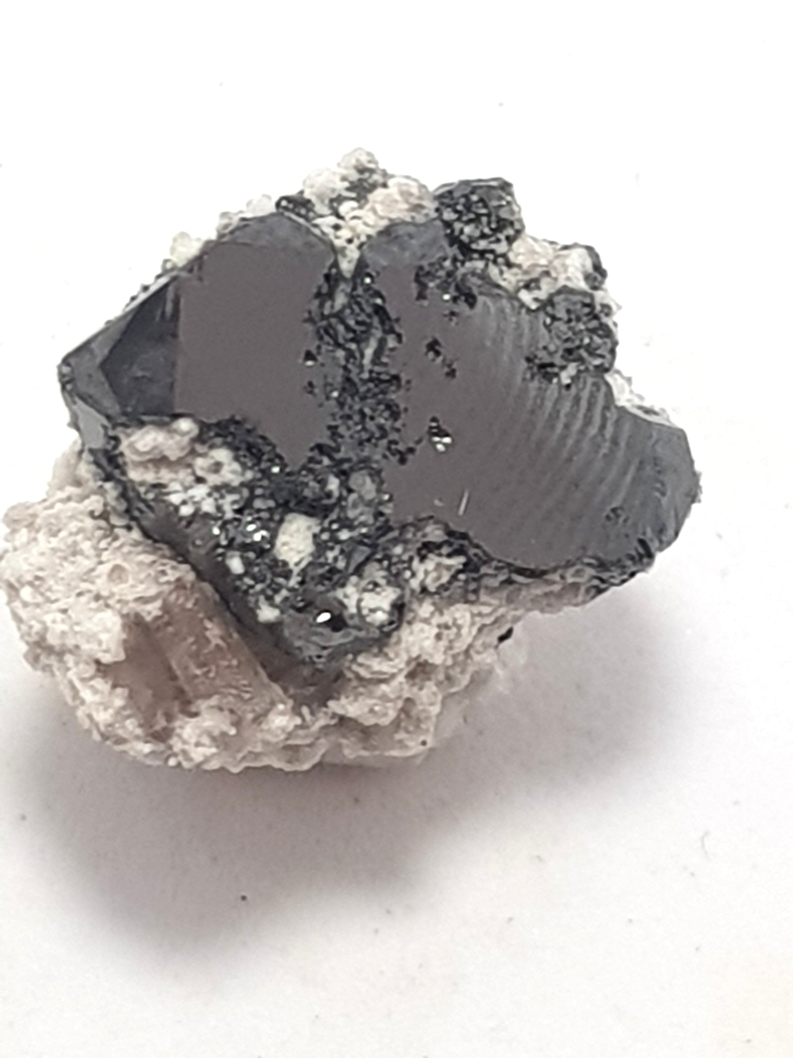 a cubic crystal of bixbyite on a white matrix