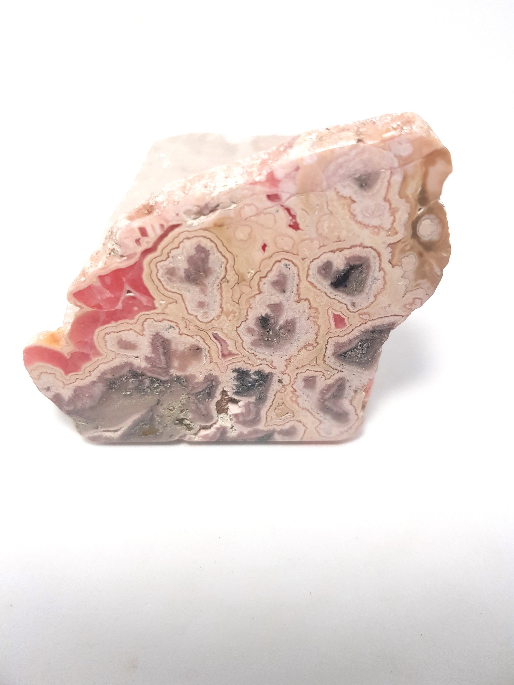 polished slice of rhodochrosite. This consists of bands of pink materials. The colours range from a deep pink to a pink tinted grey.