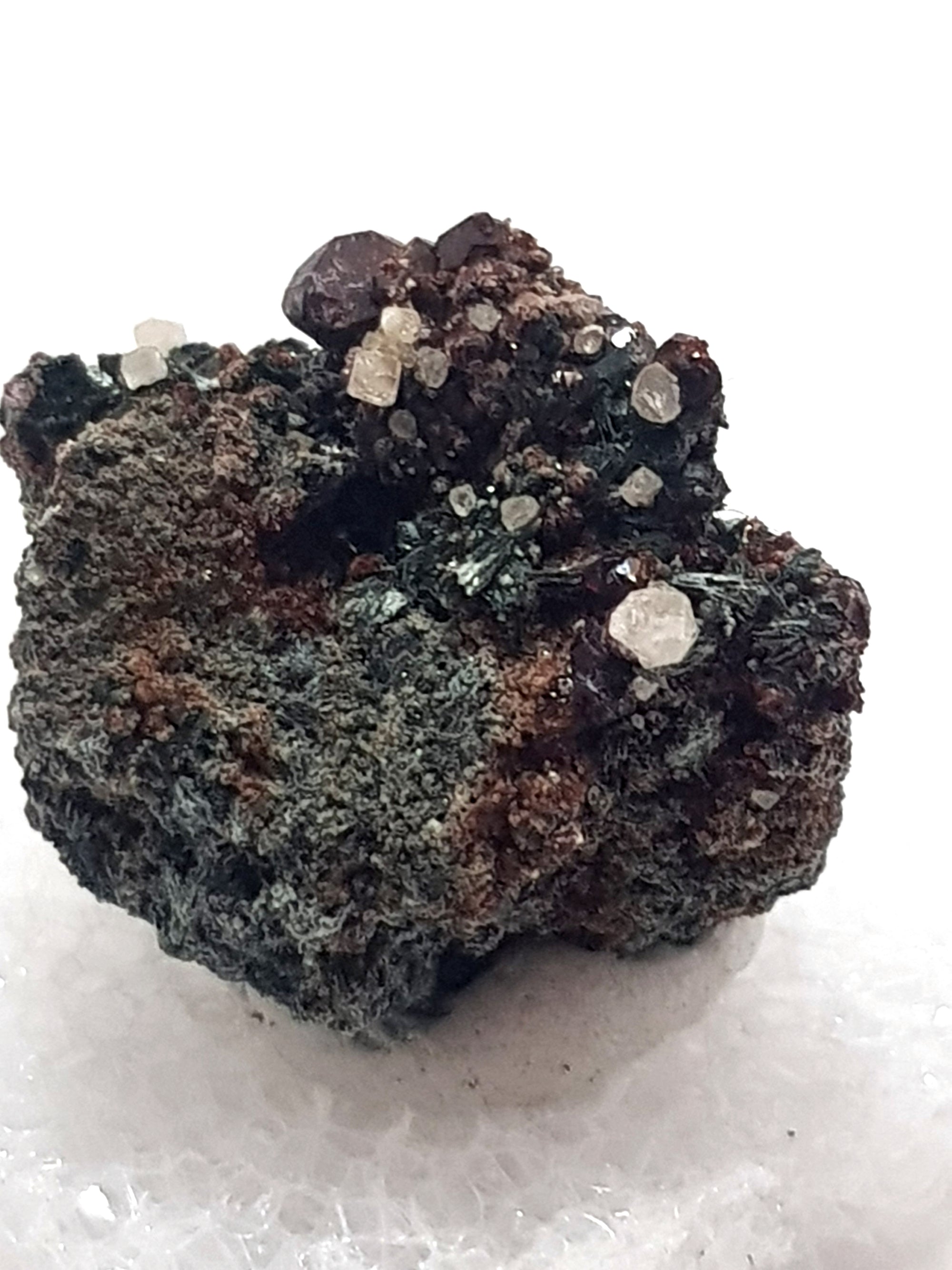 scheelite, grossular, actinolite. white crystals on a green and brown matrix.