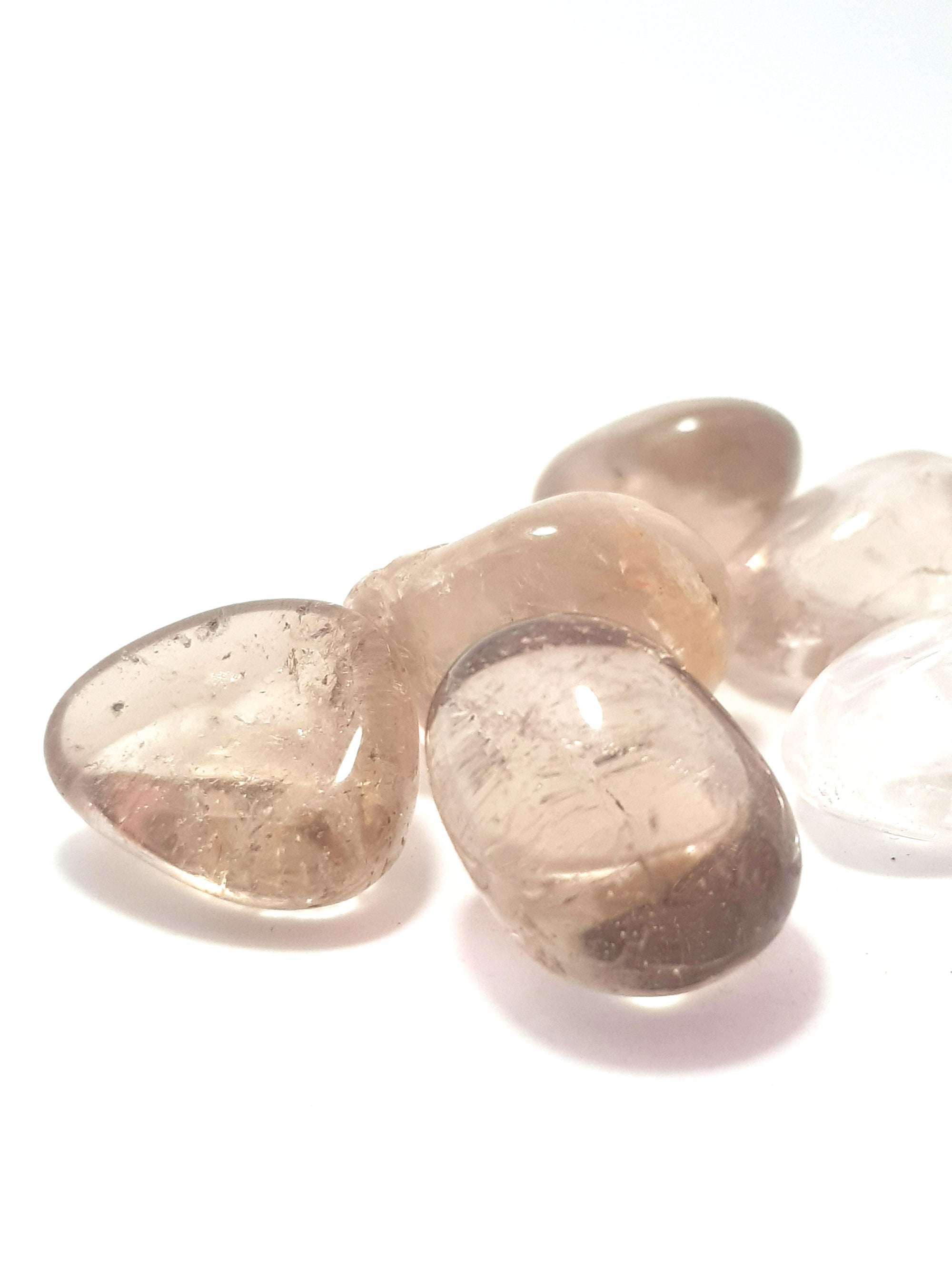 a close up of smoky quartz tumblestone. They are light grey and very translucent.