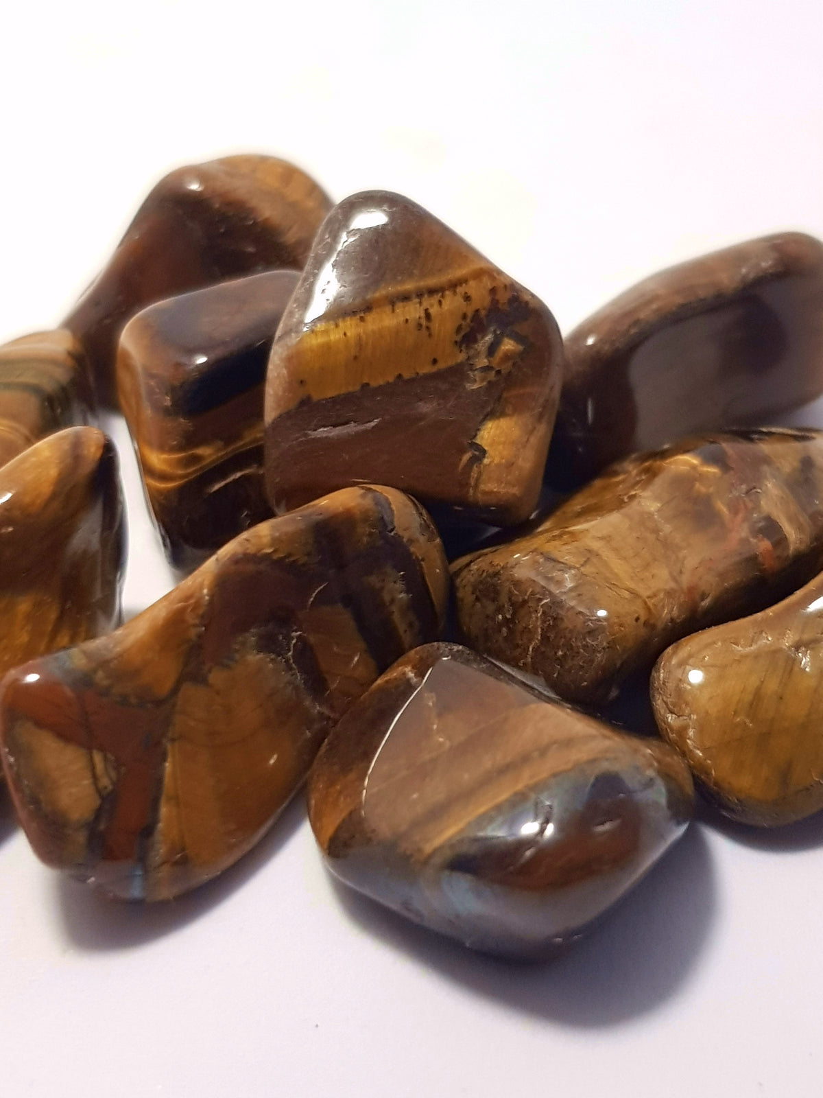 tumbled pieces of tiger eye. They are smooth but irregularly shaped.